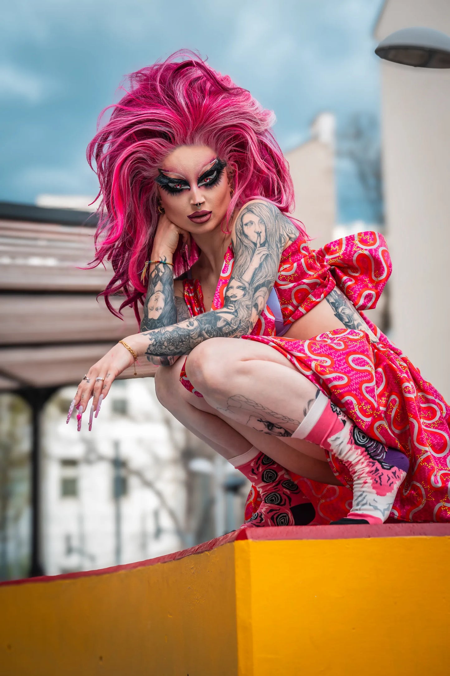 The winner of Drag Race Germany Pandora Nox squatting on a yellow surface while wearing her Official Socks Collaboration made by Play.Gay