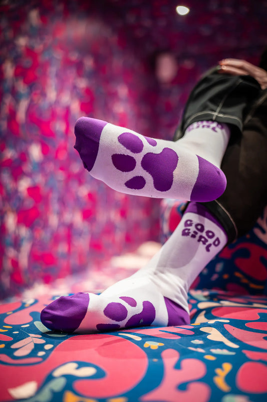 Person wearing purple socks with the title "Good Girl" and Paws at the bottom on it.
