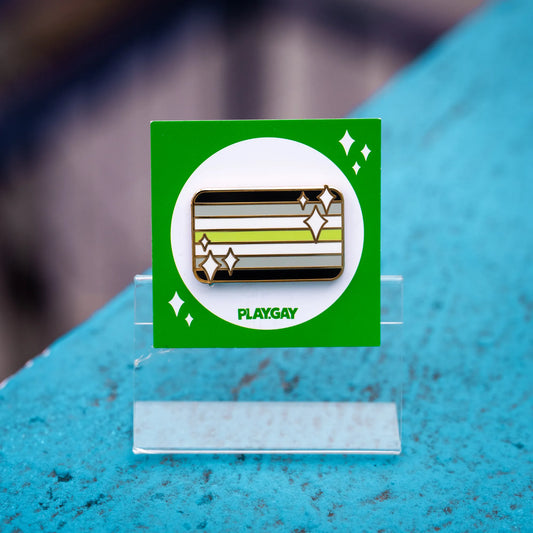 Agender pride enamel pin featuring black, grey, white, and green stripes with white sparkle accents on a green PlayGay card.