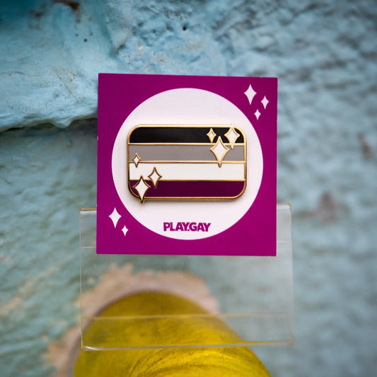 Asexual pride flag enamel pin with black, grey, white, and purple stripes, decorated with sparkles and presented on a purple PlayGay card.