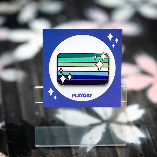 Gay male pride flag enamel pin in shades of blue, white, and green with white sparkle accents on a blue PlayGay backing card.