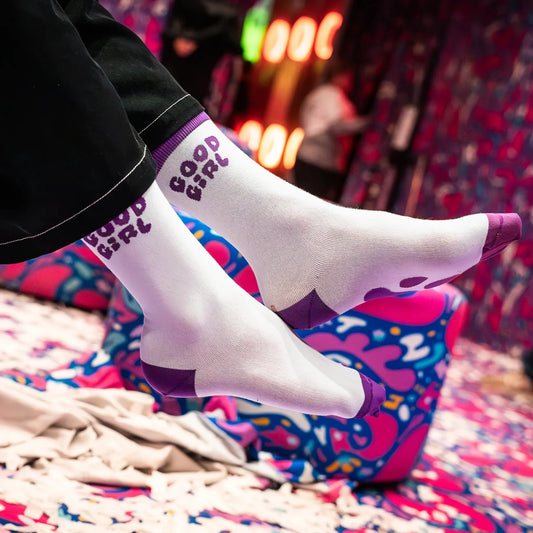 Person wearing purple socks with the title "Good Girl" on it.
