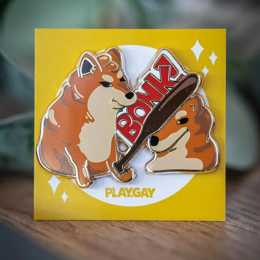 PlayGay Bonk Enamel Pin - two dogs, one bonking the other with a bat, meme-inspired hard enamel pin on yellow backing card