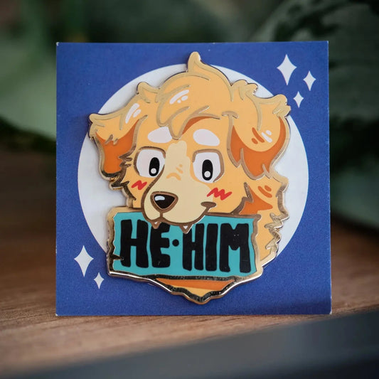 PlayGay Pronoun Dogs HE·HIM Enamel Pin - golden fluffy dog with HE·HIM banner on teal, hard enamel on blue backing card