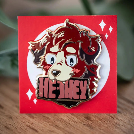 PlayGay Pronoun Dogs HE·THEY Enamel Pin – red fluffy dog with HE·THEY banner enamel pin on red backing card