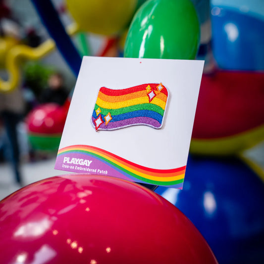 Colorful LGBTQ+ rainbow flag patch shown on a PlayGay card in a vibrant, pride-themed setting.
